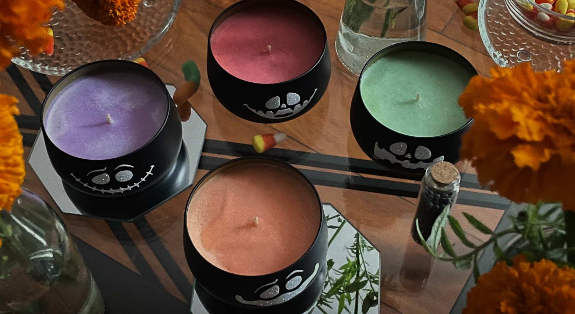 Spooky Cauldron Candles — glitter vinyl faces, shimmery wax candles. Colorful wax pops from a top down view of a Dia de Los muertos inspired halloween party table